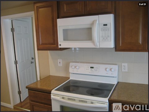 A white microwave oven is mounted above a white stove in a kitchen.