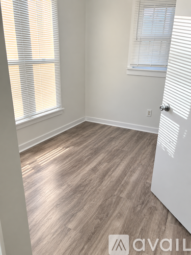 A room with a wooden floor and a window with blinds.