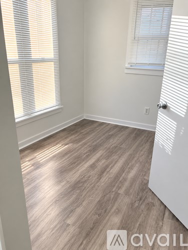 A room with a wooden floor and a window with blinds.