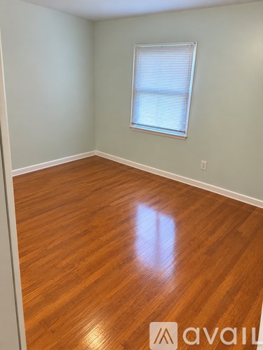 A room with wooden flooring and a window with blinds.