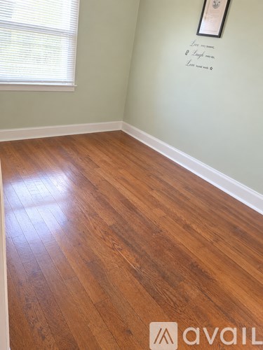 A room with wooden flooring and a framed picture on the wall.