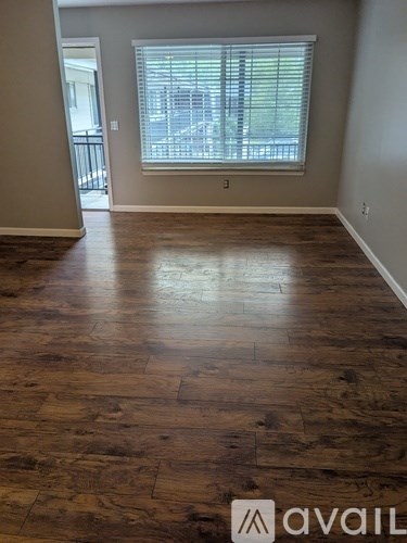 A room with wooden flooring and a window with blinds.
