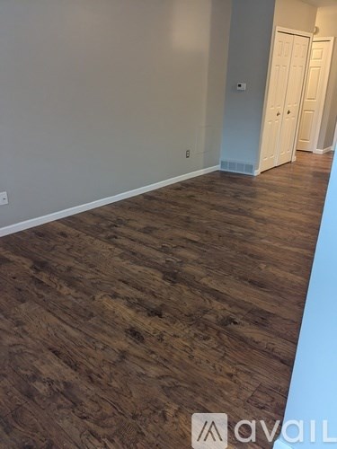 A room with wooden flooring and white walls.