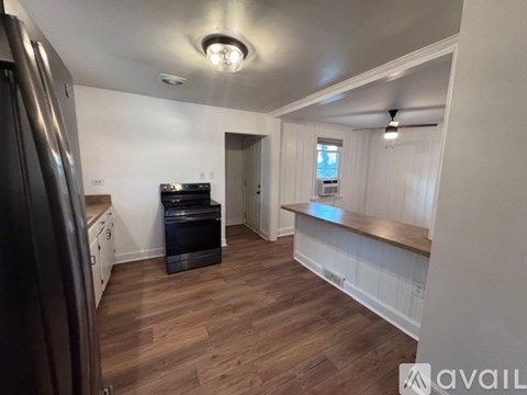 A kitchen with a refrigerator, oven, and wooden floors.