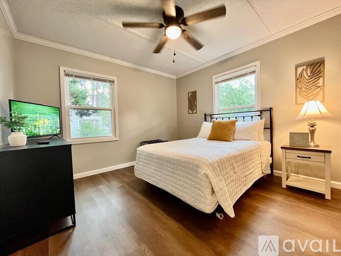 A bedroom with a bed, a dresser, and a ceiling fan.