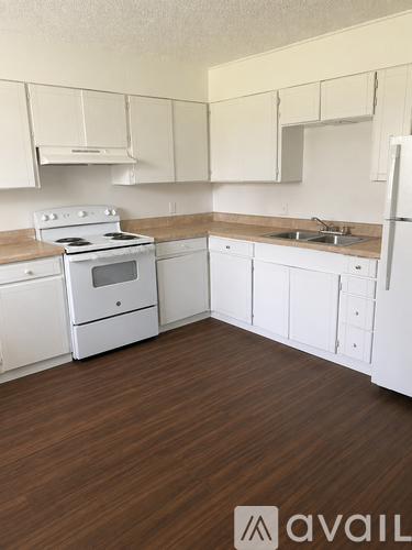 A kitchen with white appliances and wooden floors.