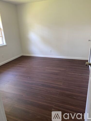 A room with wooden flooring and white walls.