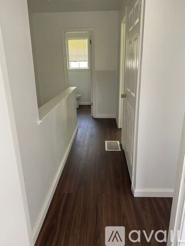 A hallway with wood flooring and white walls.