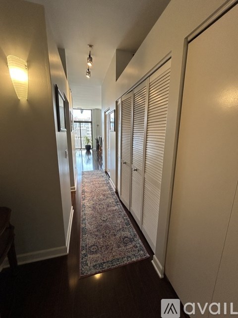 A hallway with a rug on the floor and a light on the wall.