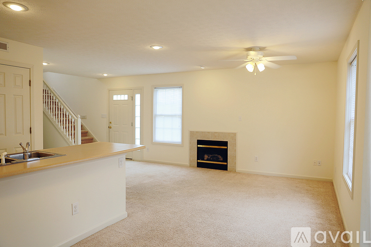 A spacious living room with a fireplace and a staircase.