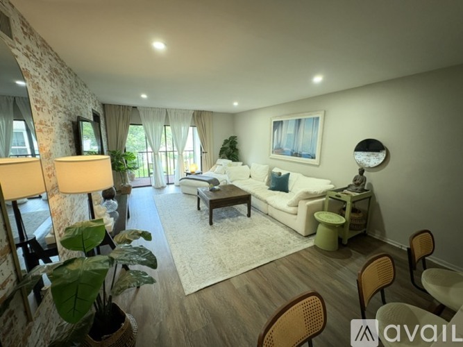 A living room with a white sofa, wooden chairs, and a painting on the wall.