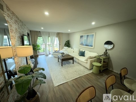 A living room with a white sofa, wooden chairs, and a painting on the wall.