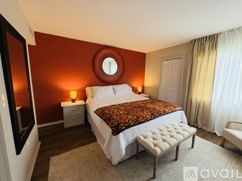 A bedroom with a round mirror on the wall and a bed with a floral patterned cover.
