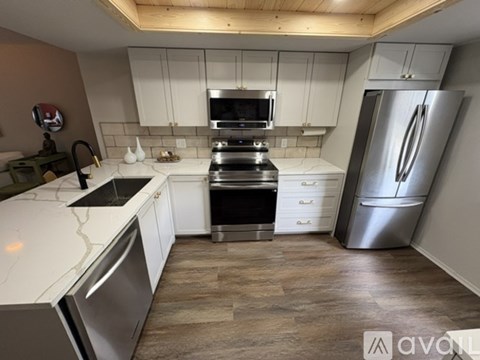 A kitchen with white cabinets and a stainless steel refrigerator.