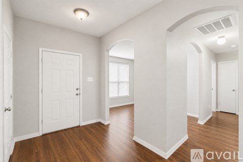 A spacious room with wooden floors and white walls.