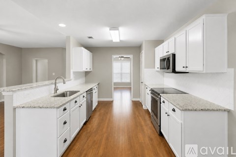 A modern kitchen with white cabinets and a granite countertop.