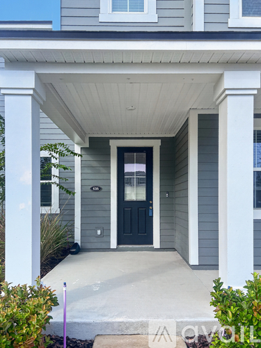 A grey house with a black door and white columns.