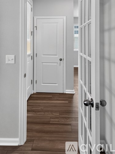 A hallway with a white door and a white wall.