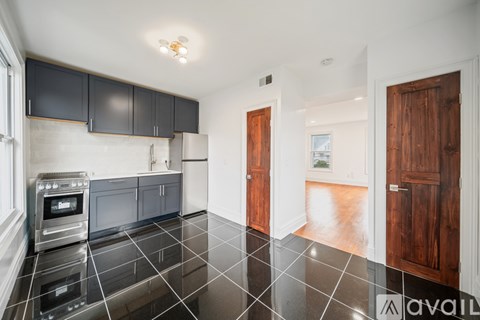 A kitchen with black cabinets and a black tile floor.