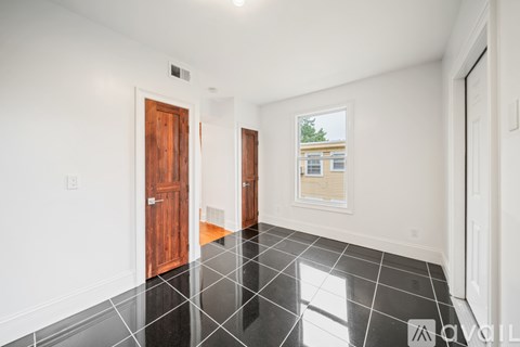 A room with a black tile floor and a window showing a building outside.