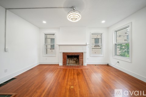 A spacious room with a fireplace and wood flooring.