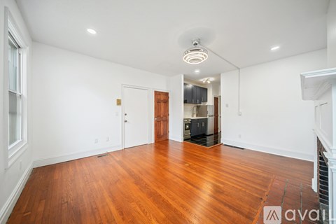A large empty room with wooden floors and white walls.