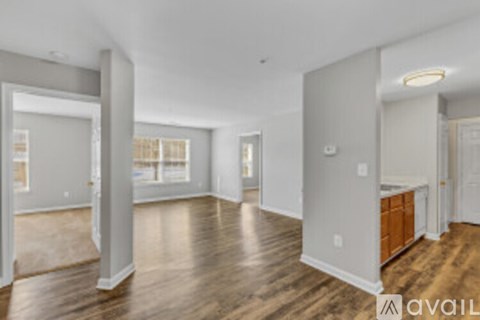 A spacious room with wood flooring and white walls.