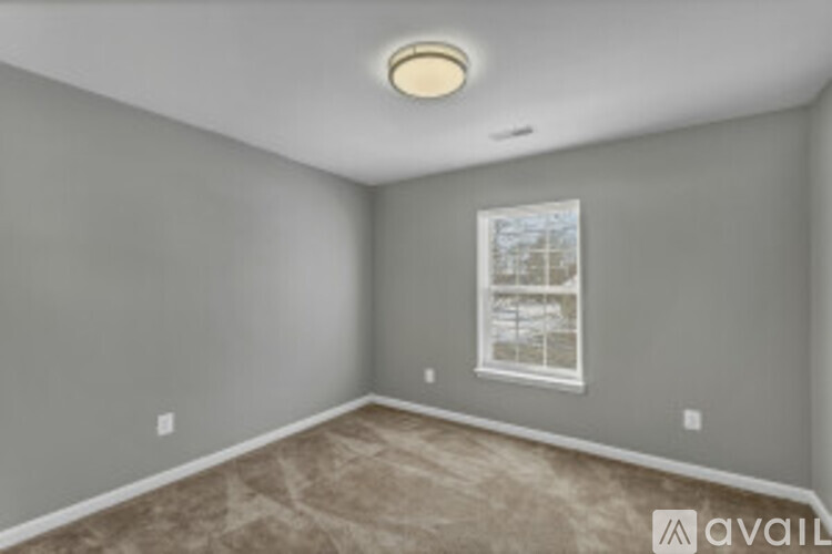 A room with a window and a carpeted floor.