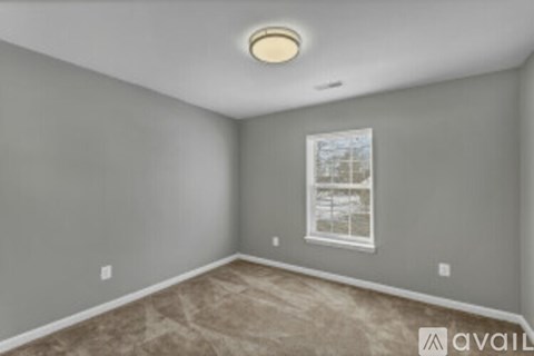 A room with a window and a carpeted floor.