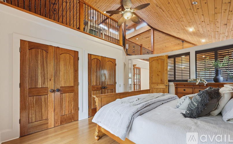 A bedroom with a bed, wooden wardrobe, and a ceiling fan.