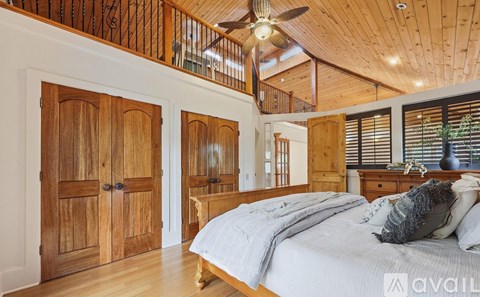 A bedroom with a bed, wooden wardrobe, and a ceiling fan.