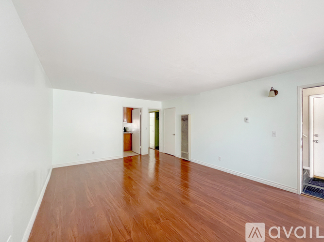 A room with wooden floors and white walls, with a door on the right side.