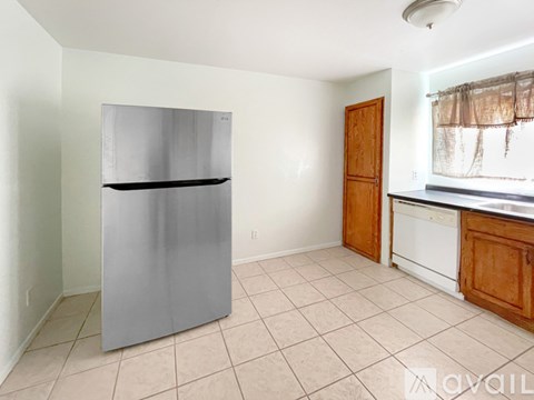 A kitchen with a fridge, dishwasher and wooden cabinets.