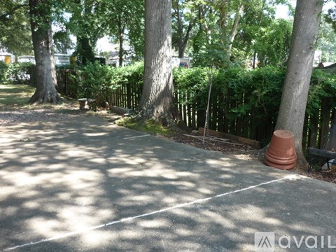 A concrete area surrounded by trees and a fence.