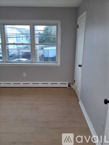 A room with a white door and a window with a view of a parking lot.