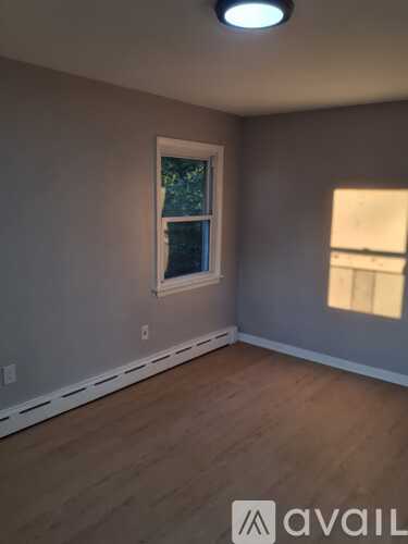 A room with a window and wooden flooring.