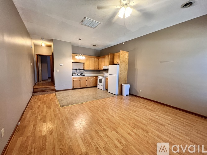 A kitchen area with wooden floors and a white refrigerator.