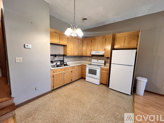 A kitchen with white appliances and wooden cabinets.