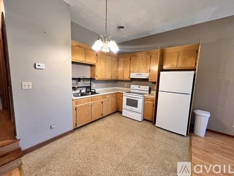A kitchen with white appliances and wooden cabinets.