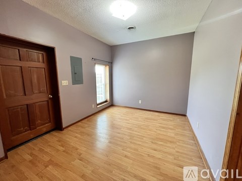 A room with wooden flooring and a brown door.