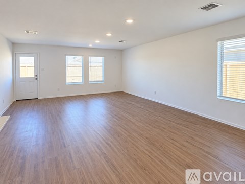 A spacious room with wooden flooring and white walls.