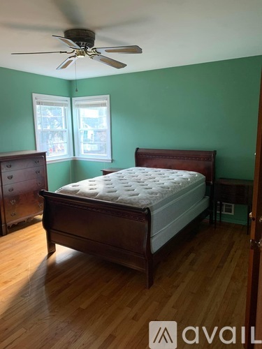 A bedroom with a bed, dresser, and window.