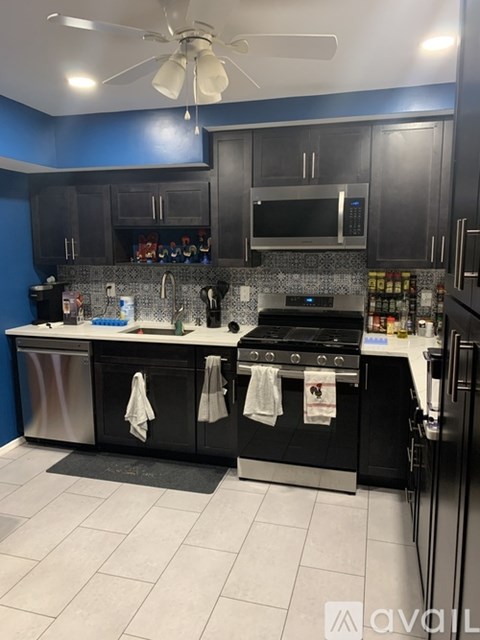 A kitchen with black cabinets and a stainless steel dishwasher.