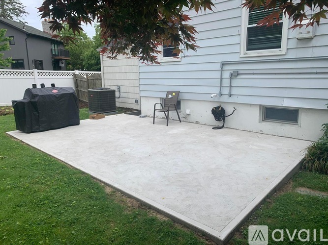 A patio with a concrete floor and a grill on it.