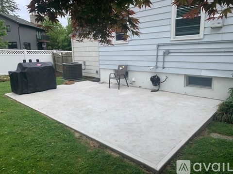 A patio with a concrete floor and a grill on it.