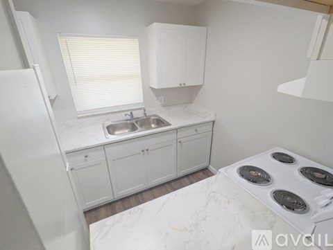 A kitchen with white cabinets and a stove top oven.