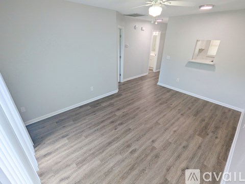 A spacious room with wooden flooring and white walls.