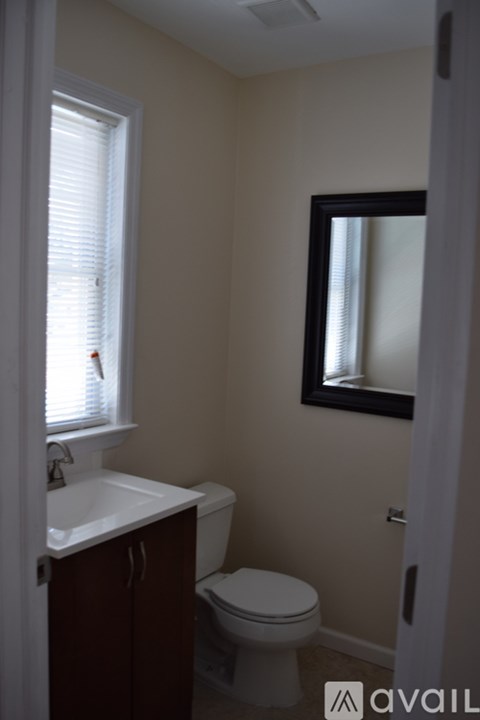 A bathroom with a toilet, sink, and window.