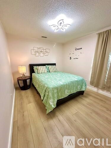 A bedroom with a bed, nightstand, and a wall decoration.