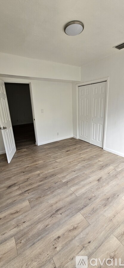 A room with wooden flooring and white walls.